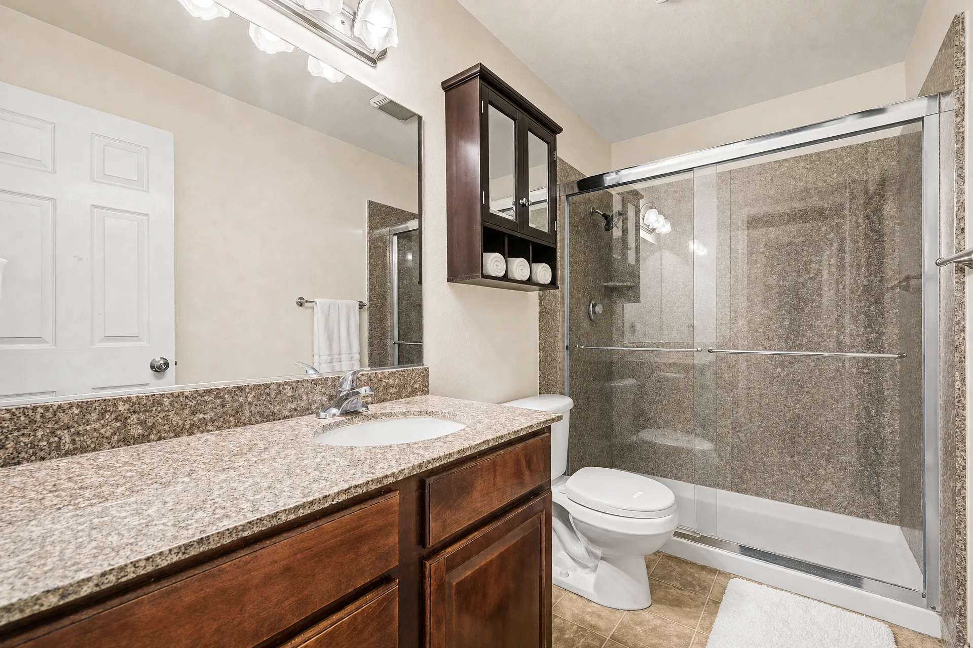 Virtually staged bathroom with a granite vanity and walk-in shower