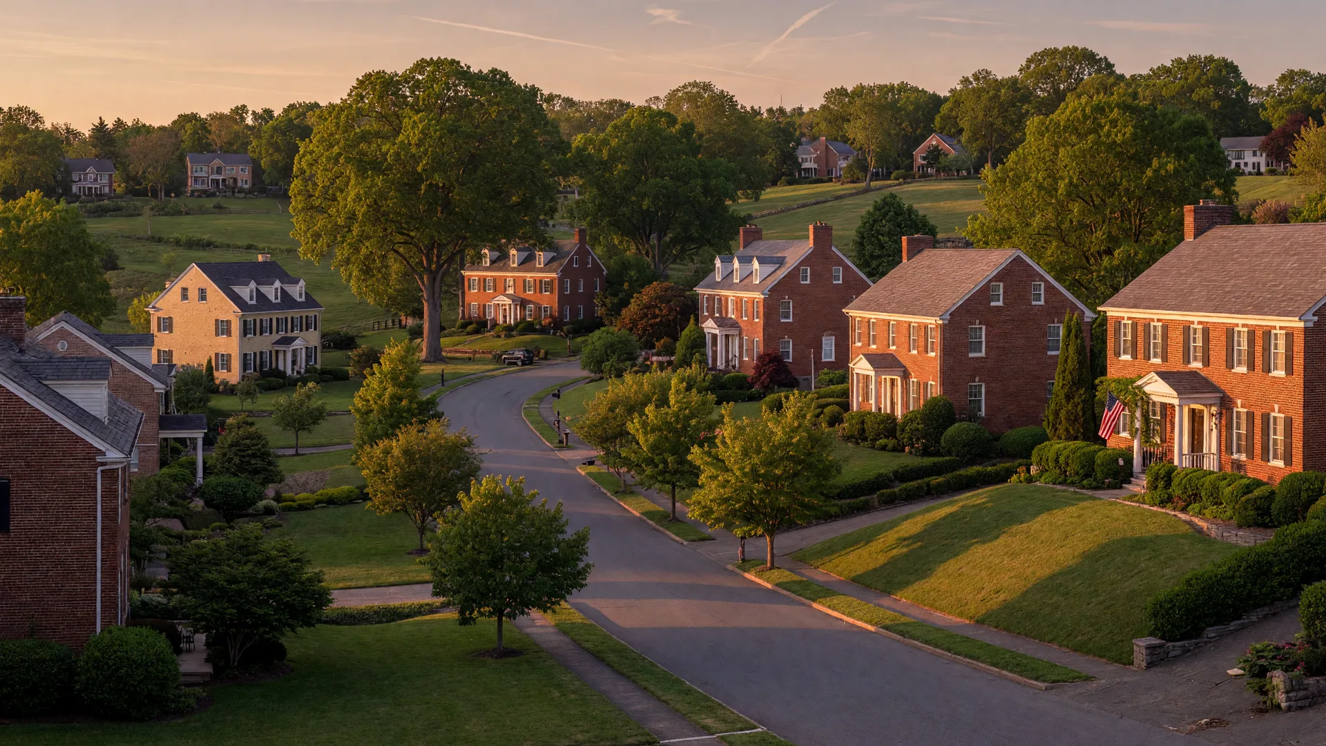 A panoramic view of a stately Northern Virginia estate at golden hour, with brick homes and mature trees on rolling hills