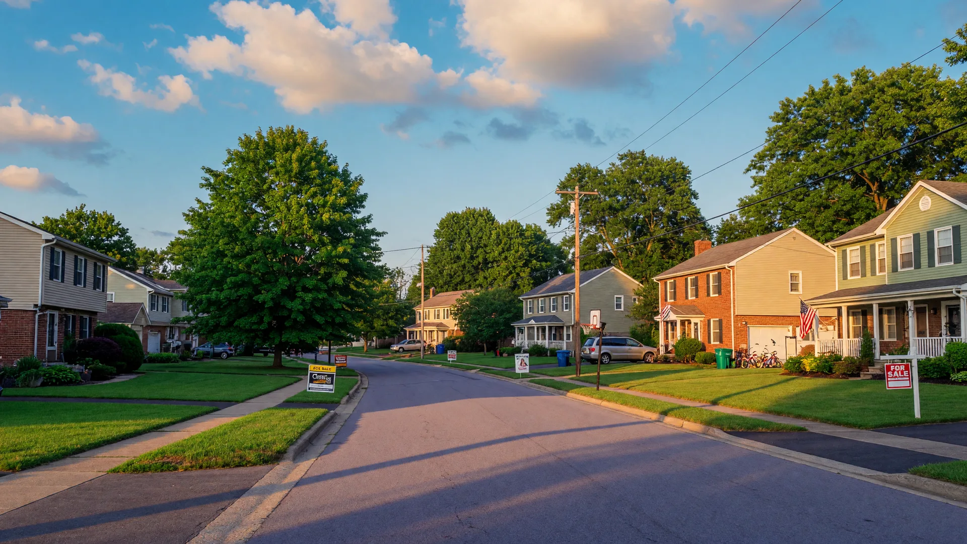 A tree-lined suburban street in Hamilton County with For Sale signs on a warm summer afternoon
