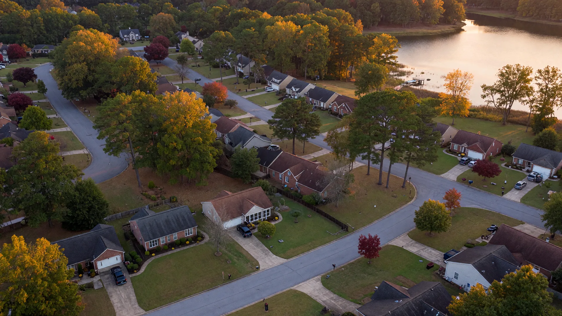 Aerial view of a suburban neighborhood in the Columbia, SC Midlands in mid-October, with autumn color in the trees and a lake cove in the distance