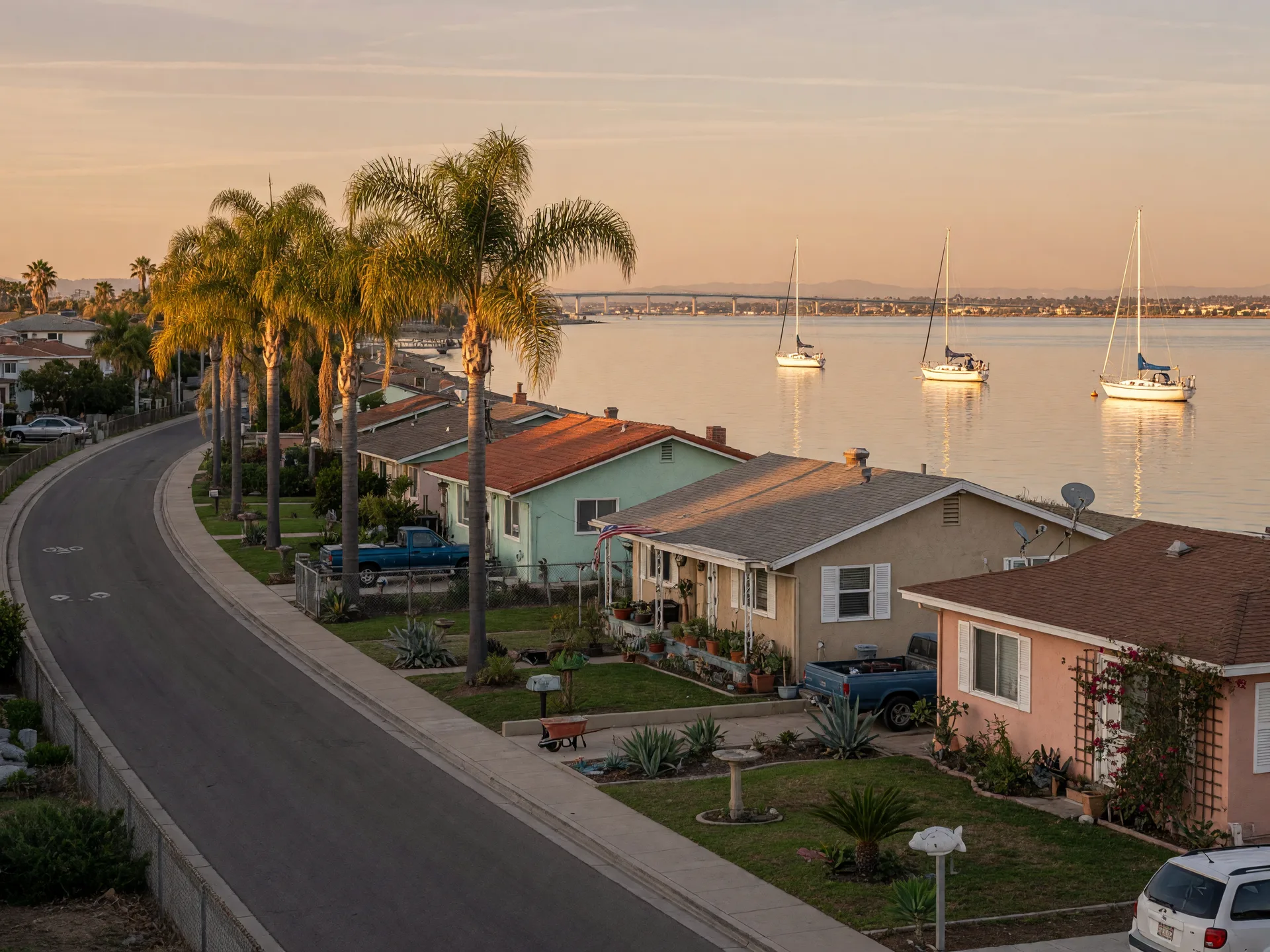 The Bayshore Bikeway beside calm San Diego Bay water near the bayside residential blocks of Imperial Beach, with palm trees and low homes