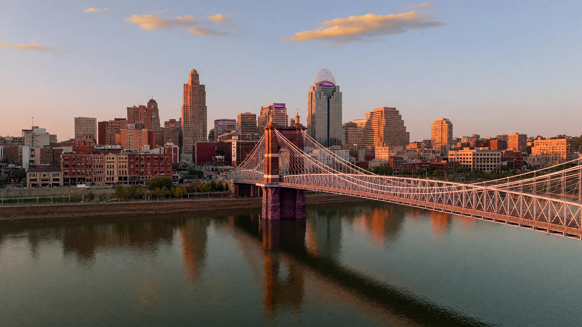 The Roebling Suspension Bridge spanning the Ohio River with the downtown Cincinnati skyline behind it at golden hour