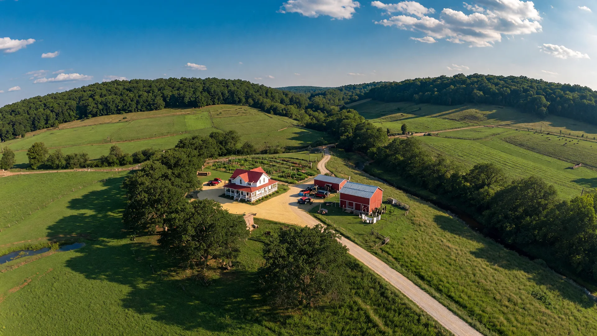 Aerial drone photography of a Missouri Ozarks farmhouse with rolling hills and mature trees