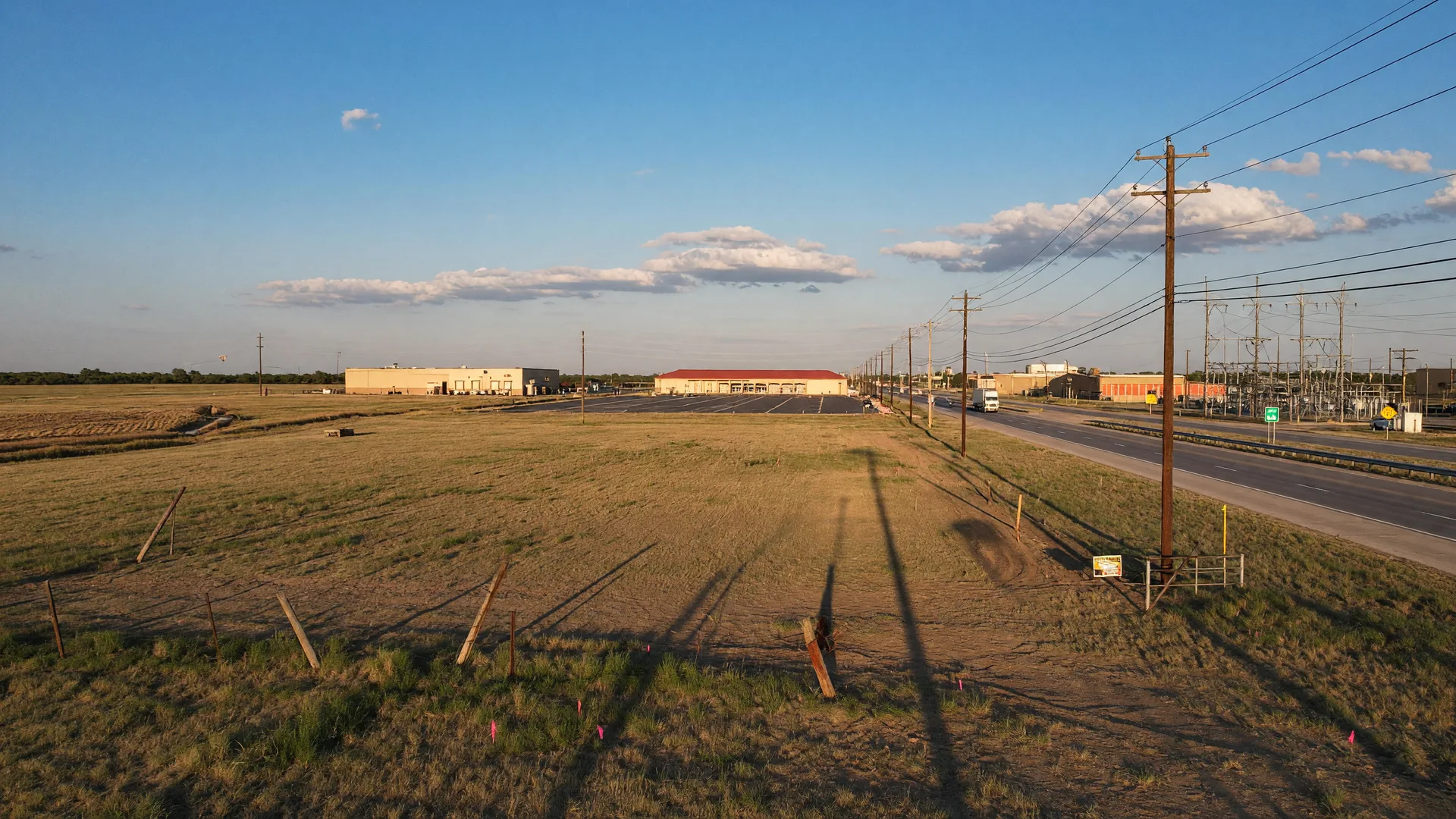 A large open field along a Texas highway with visible utility infrastructure and road frontage suggesting development potential
