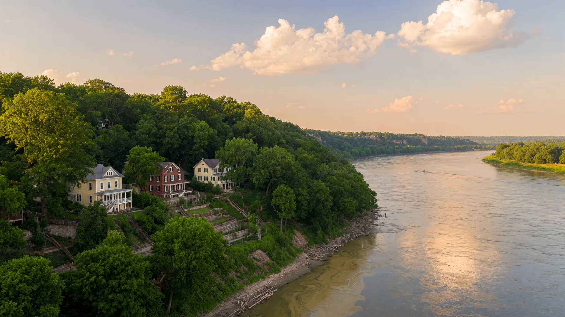 Scenic Missouri River bluffs in Parkville with lush greenery and elegant hillside homes on a golden summer afternoon