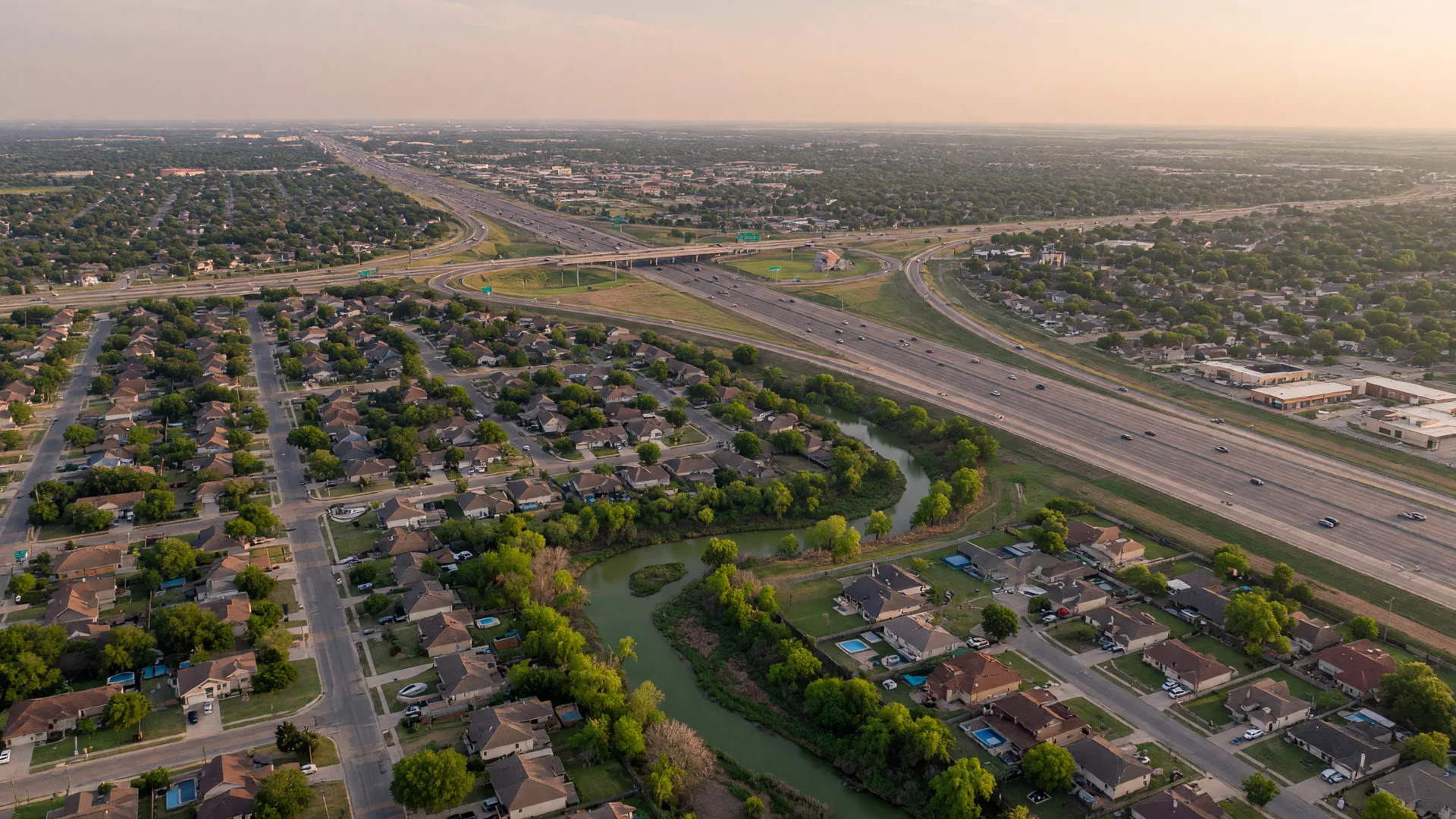Aerial view of suburban subdivisions, a tree-lined creek and the I-35 corridor in the Selma, Texas area