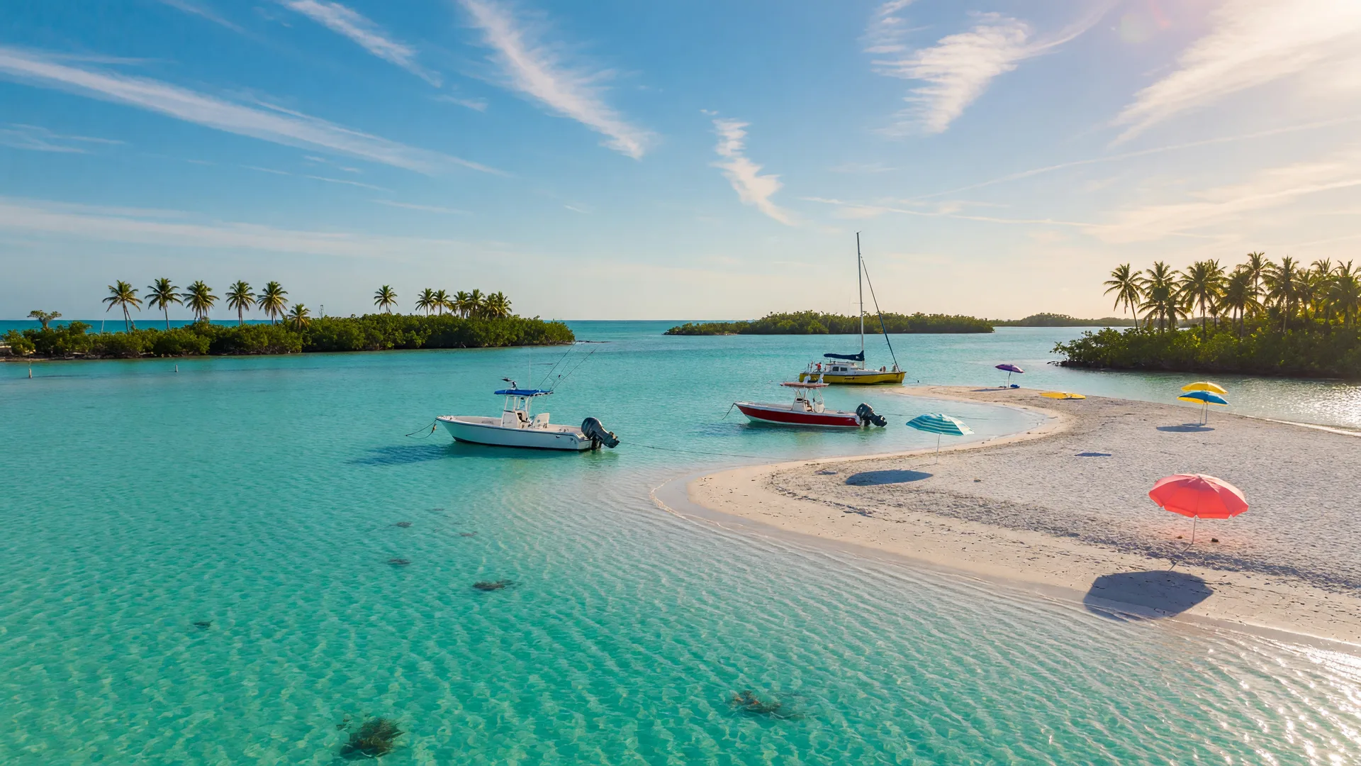 Boats anchored in waist-deep crystal-clear turquoise water over white sand at a Florida Keys sandbar, with beach umbrellas and palm-lined islands in the distance on a bright late-September day