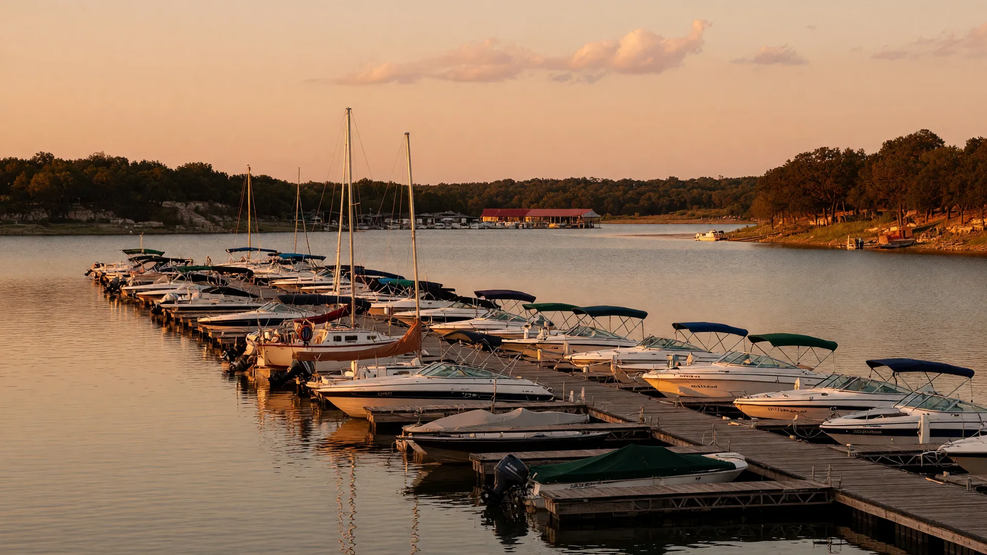 Boats moored along a wooden dock at a Lake Texoma marina, calm water glowing in golden hour light