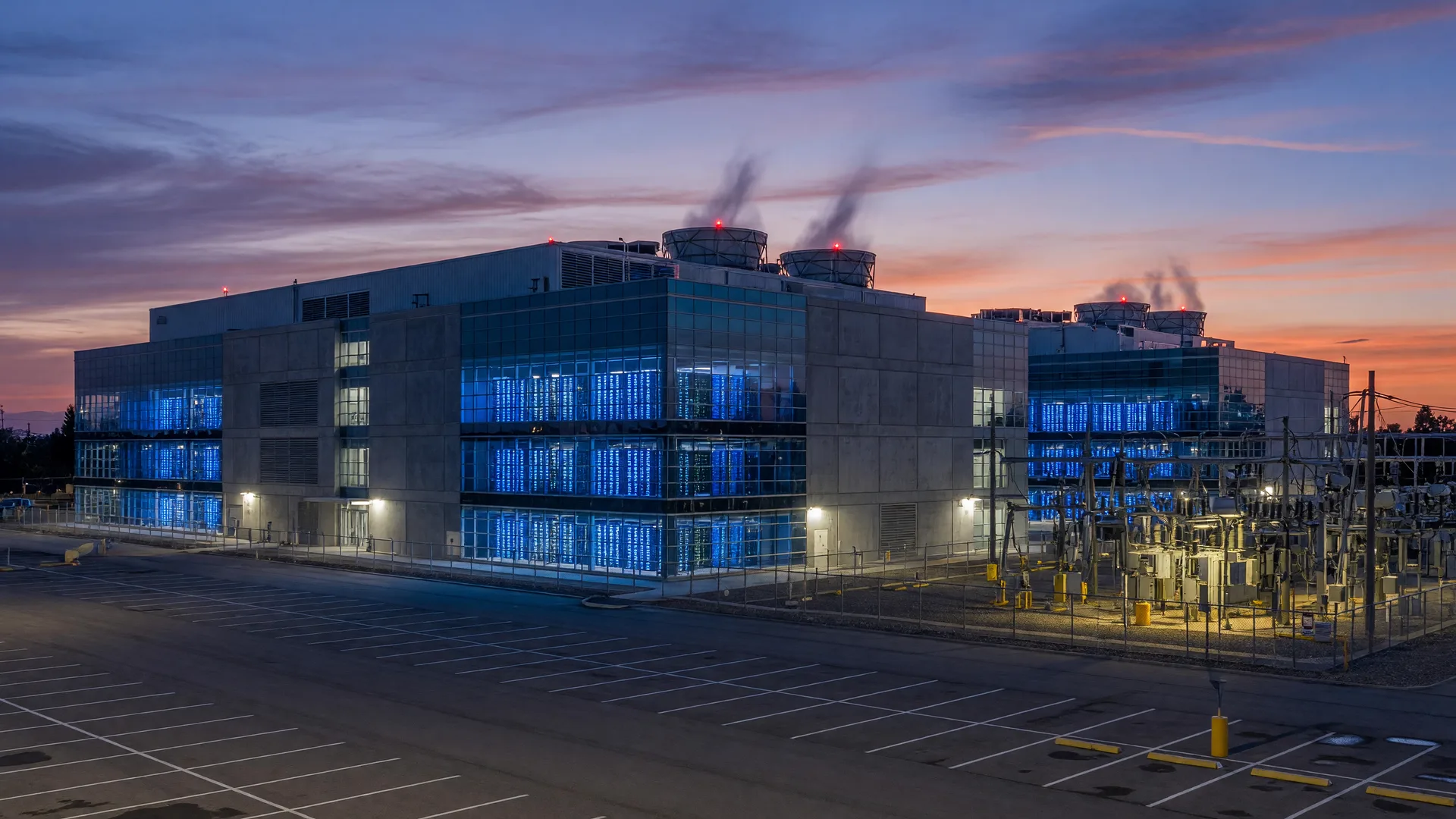 Modern data center facility at twilight with glowing server racks and cooling towers