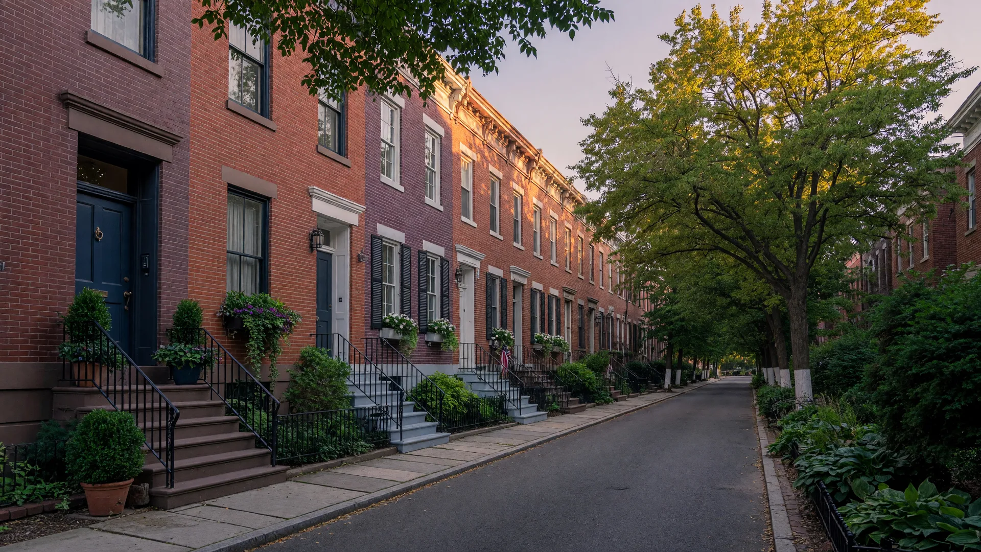A row of elegant brick EYA townhomes on a tree-lined street in a walkable Northern Virginia neighborhood at evening light