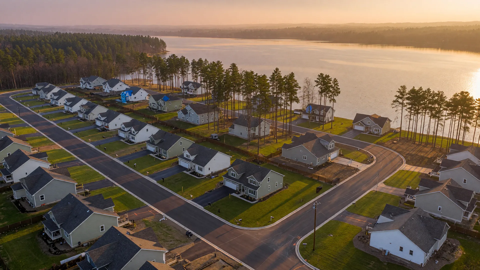 Aerial view of a growing lakeside community with new streets at golden hour