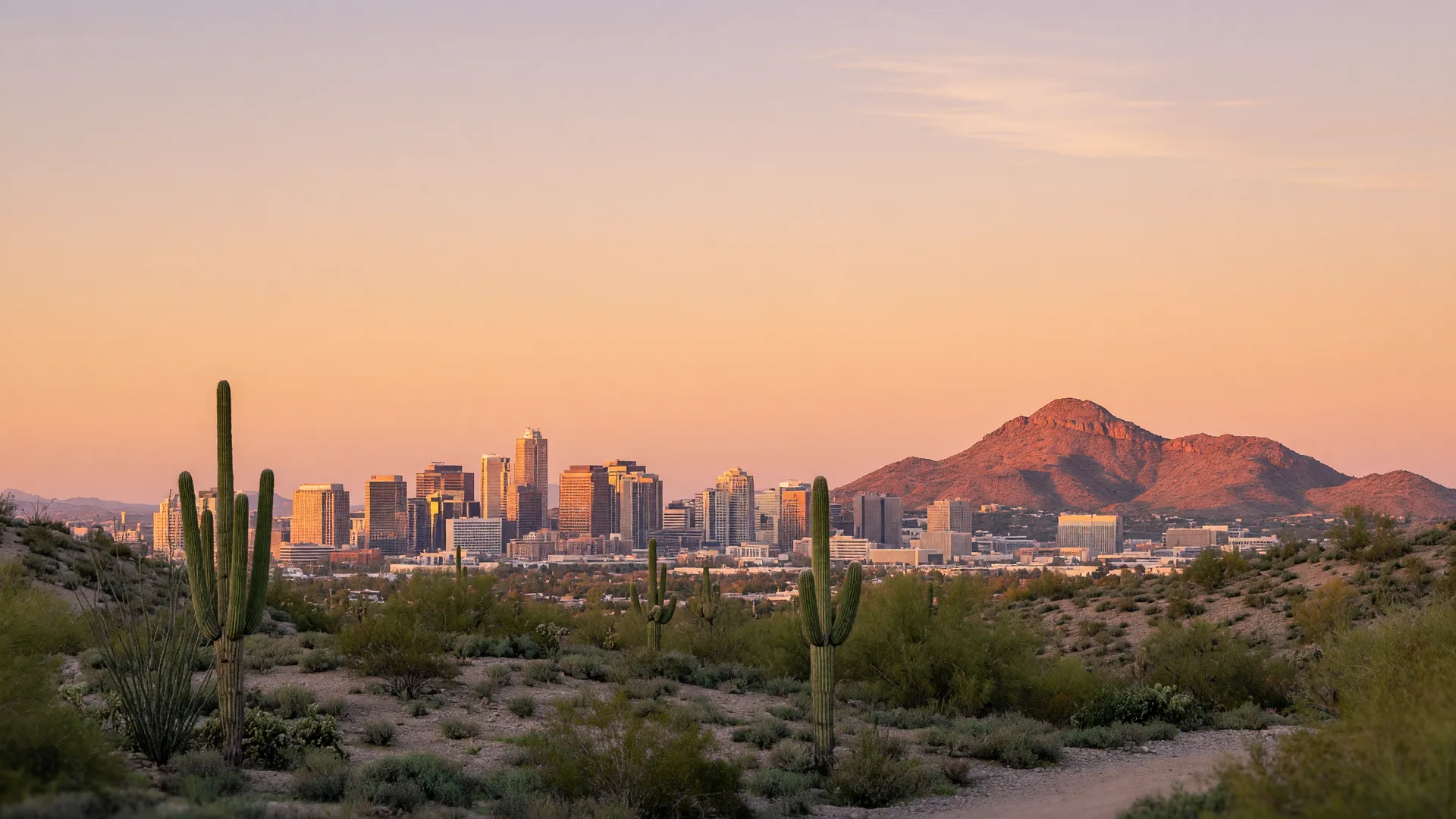Phoenix skyline at golden hour with saguaro cacti in the foreground