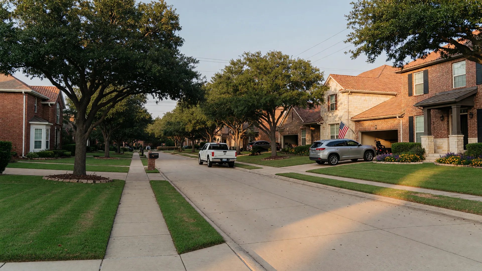 A wide view of a quiet tree-lined residential street in a Texas master-planned community in late-afternoon light