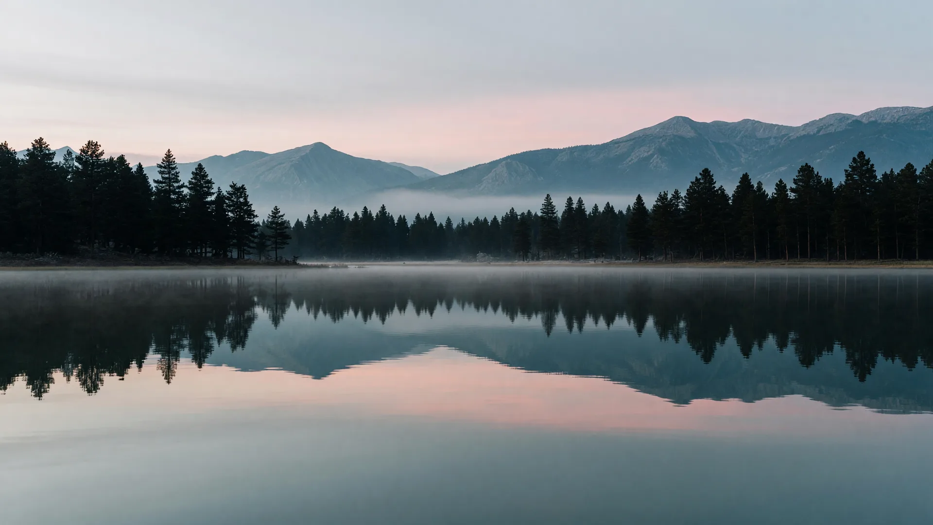 Serene mountain lake at dawn with mirror-still reflections of pines and mountains
