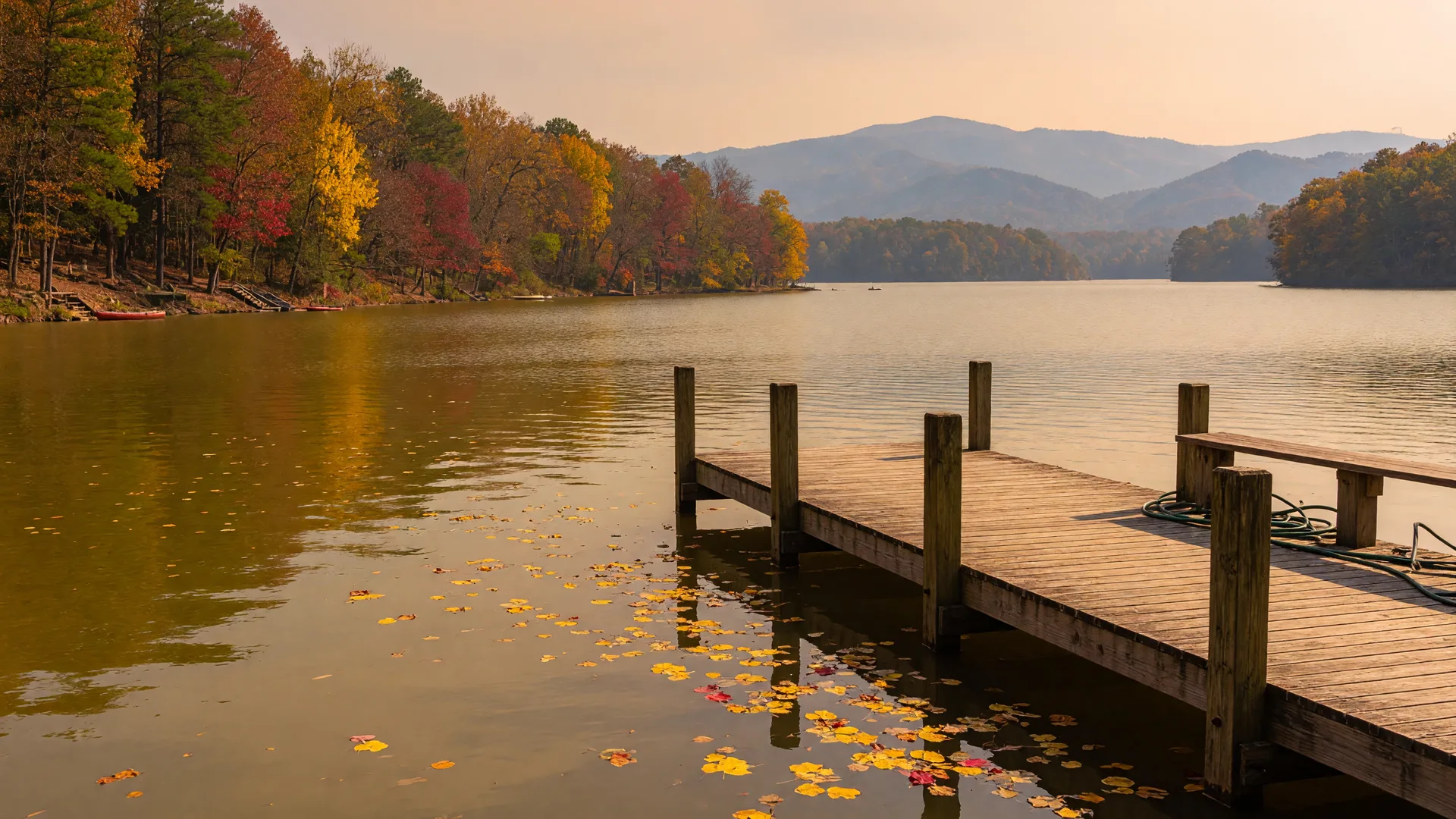 A private dock on a Northeast Georgia lake at golden hour with autumn color along the shoreline