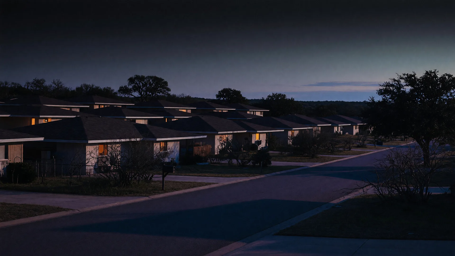 Dusk view of a quiet suburban street in Texas hill country with single-story homes