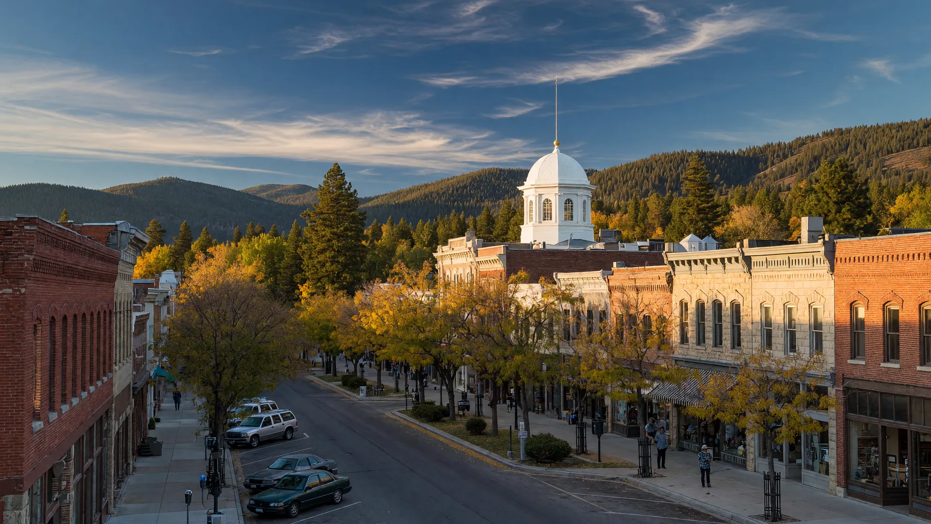 Downtown Carson City, Nevada at golden hour, with historic storefronts, the state capitol dome, and the Sierra Nevada foothills behind the town.