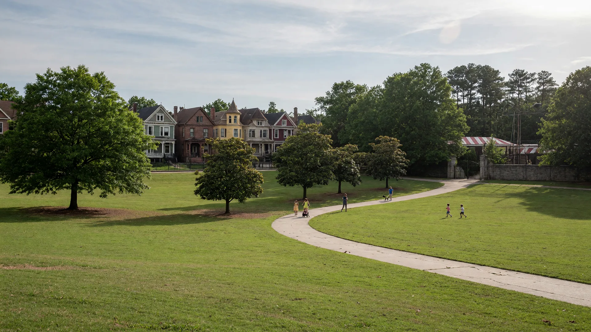 The green lawn and mature trees of Grant Park with a walking path and historic homes in the distance
