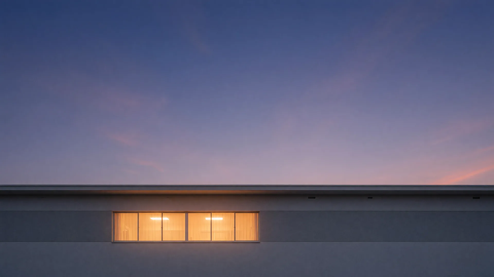 A long, low single-story roofline against a soft evening sky