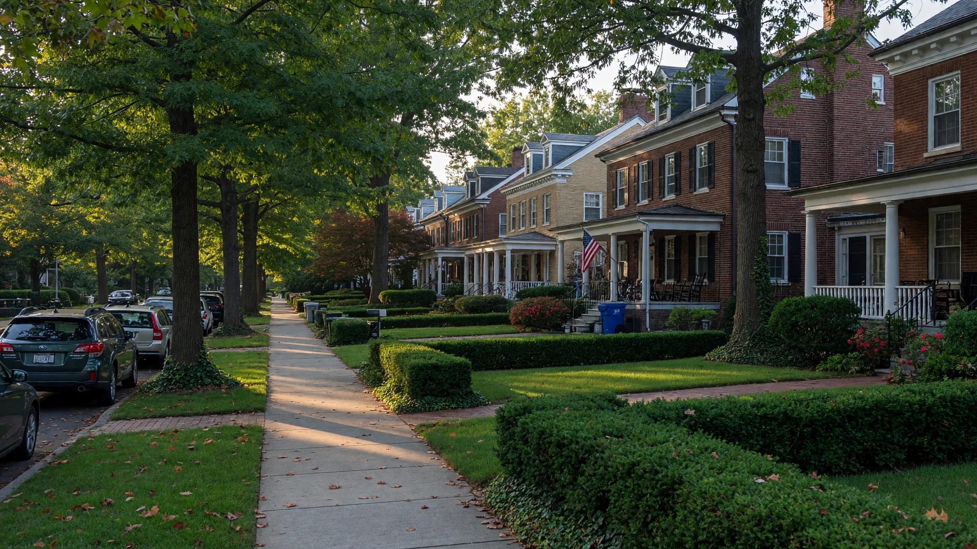 A quiet Chevy Chase, DC street of brick colonial homes with front porches and mature shade trees in golden-hour light