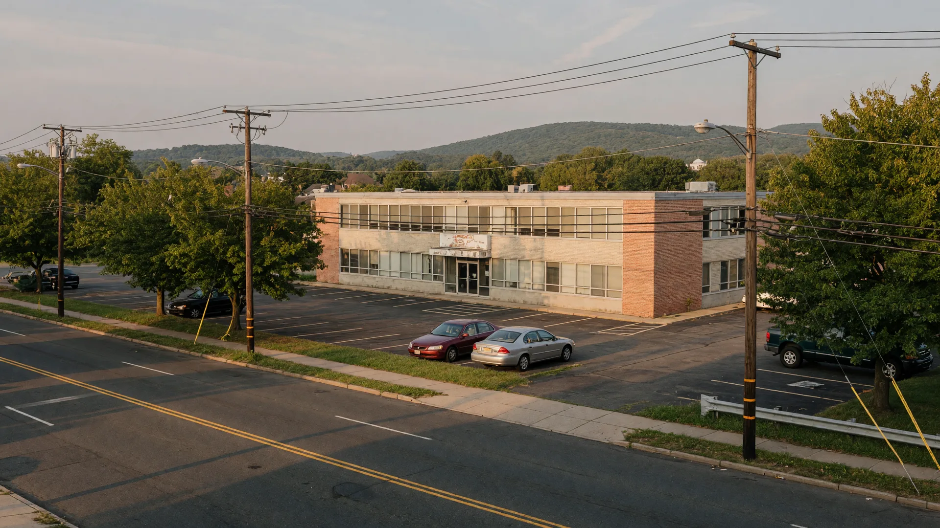 A dated flat-roofed brick-and-glass commercial office building set back from Pleasant Valley Way in West Orange NJ with a parking lot and street trees