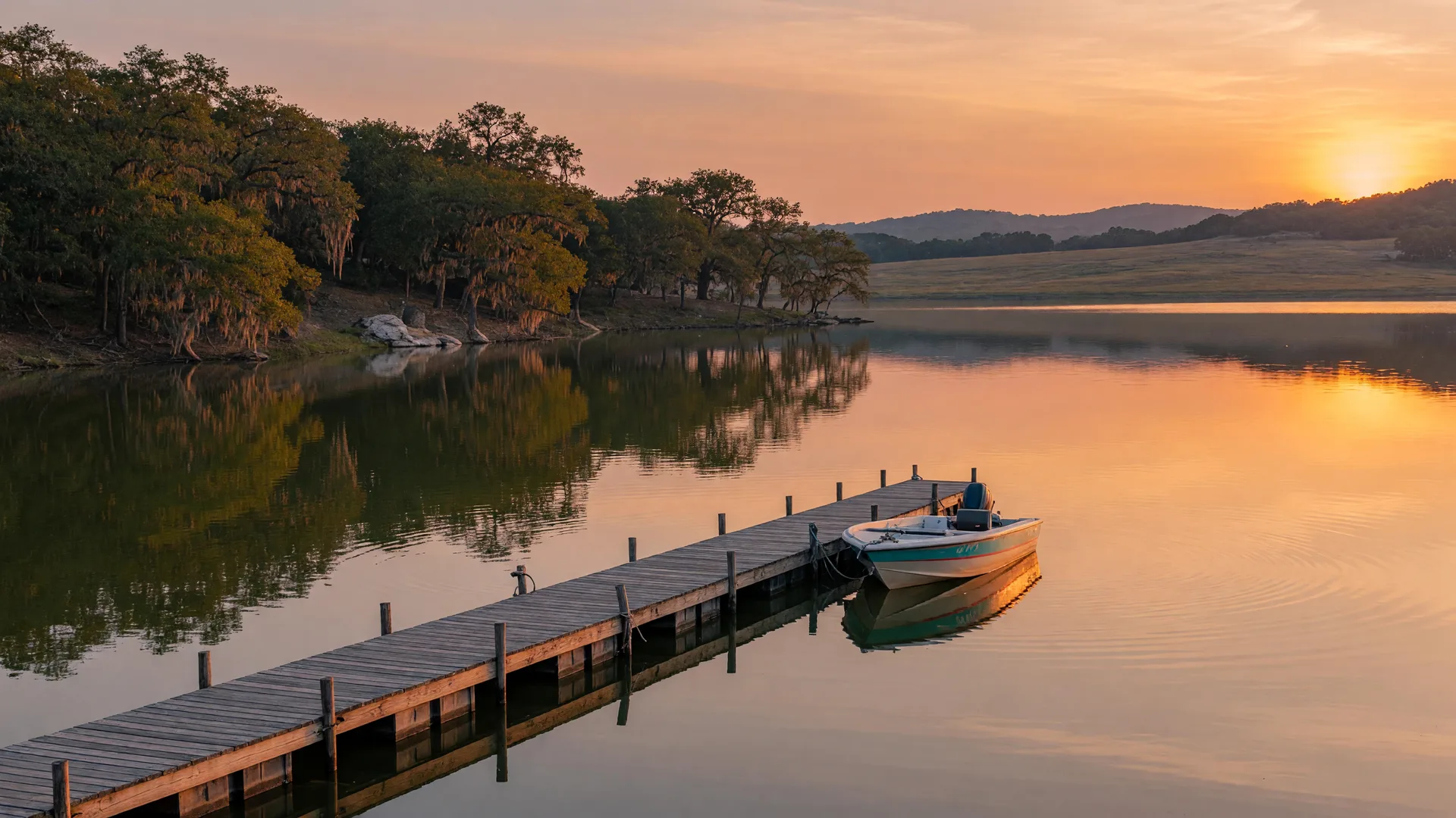 A calm central Texas reservoir at golden hour with a wooden dock and a runabout boat