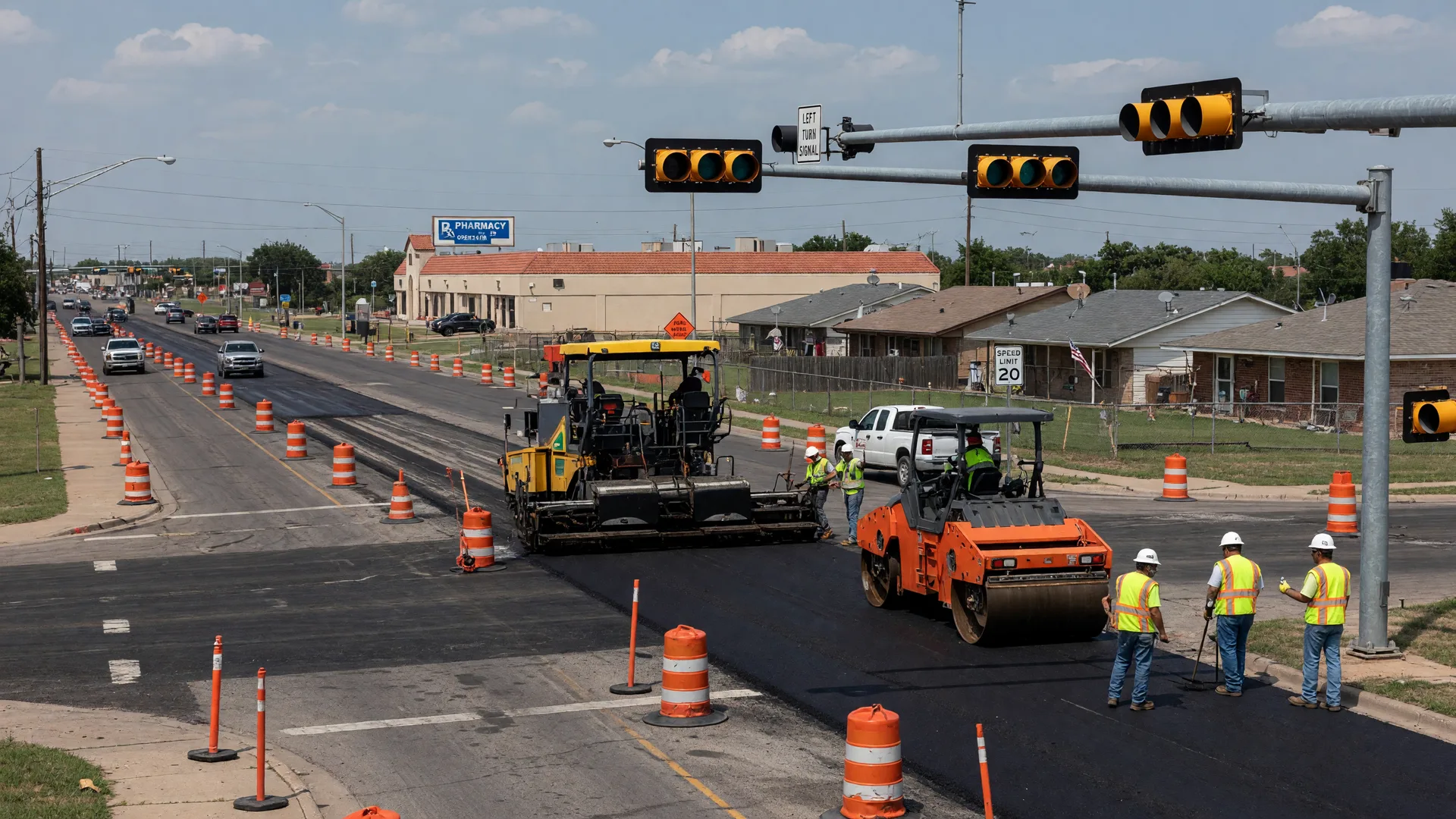 A suburban Texas intersection under active road construction with orange barrels and fresh asphalt