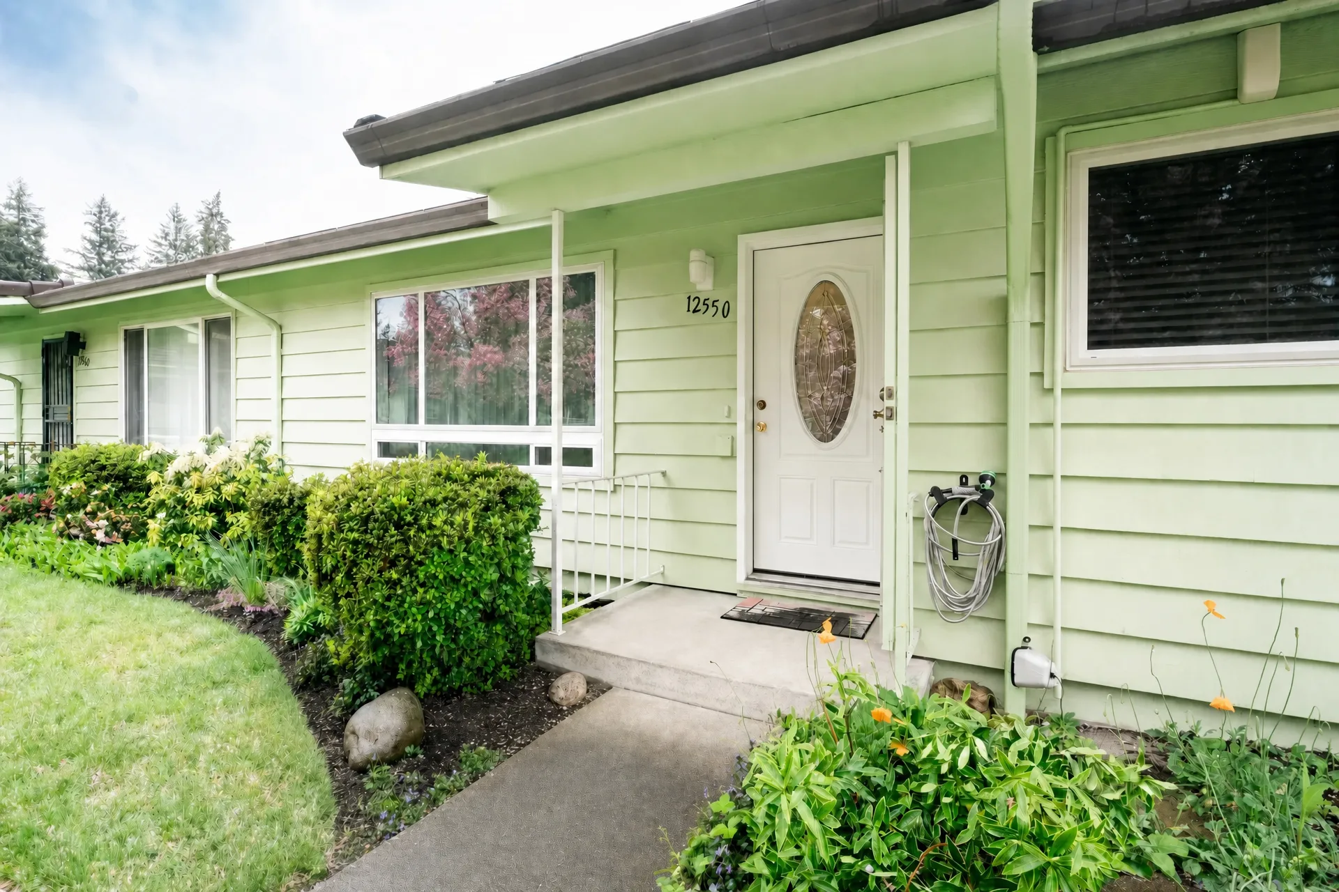 Front facade of the one-level condo at 12550 SE Main St with light green siding and white trim
