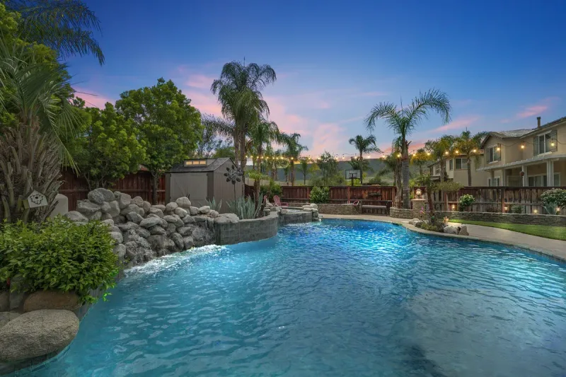 Twilight view of a well-presented Murrieta backyard with a pool and string lights