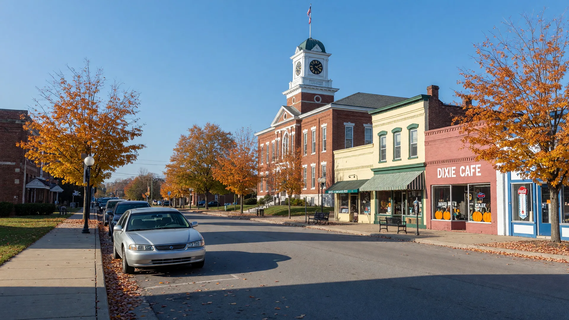 A silver sedan parked on a quiet Kentucky main street with a brick county courthouse and clock tower at the end of the block