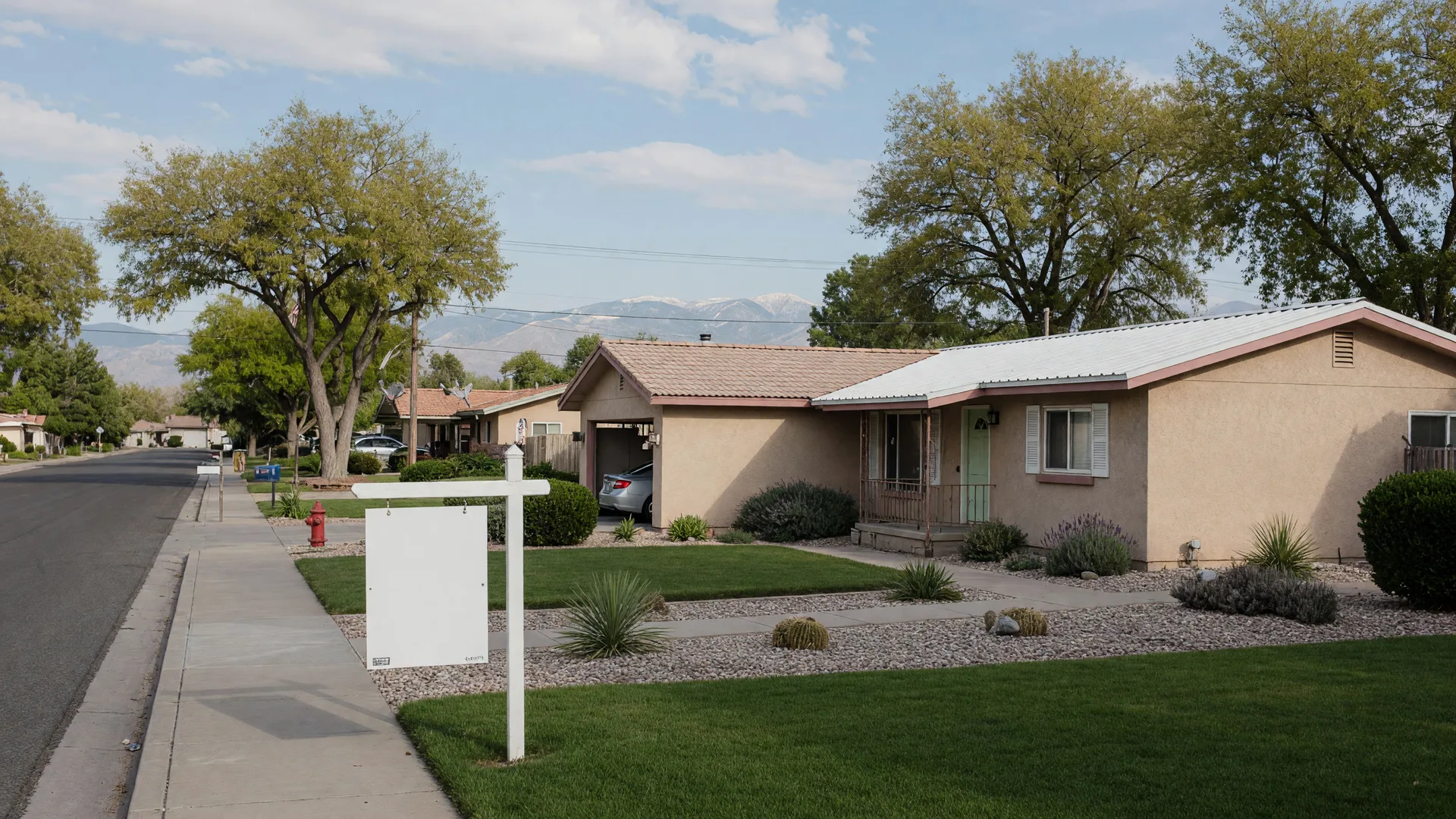 A well-kept single-story Carson City home with a for-sale sign in the front yard under a warm morning sky, with foothills in the distance.