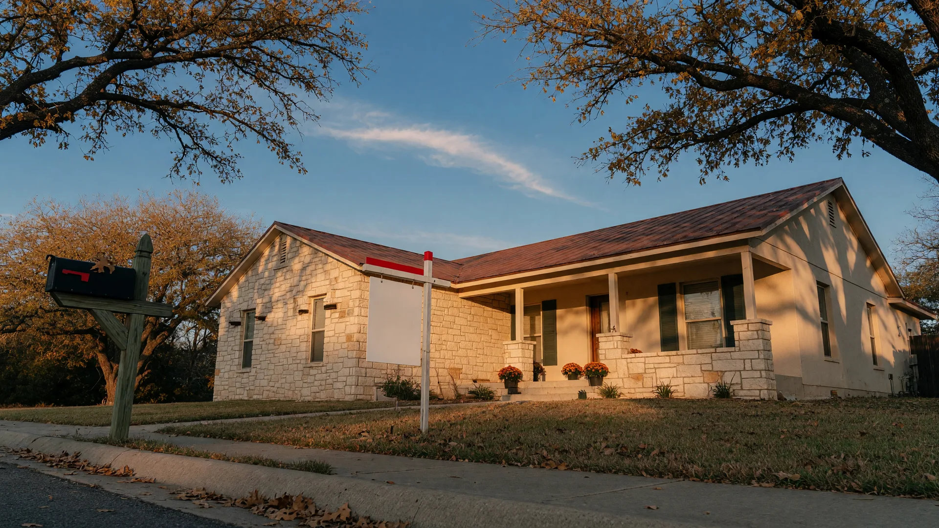 A single-story Texas Hill Country home with a for sale sign in the front yard in warm fall morning light
