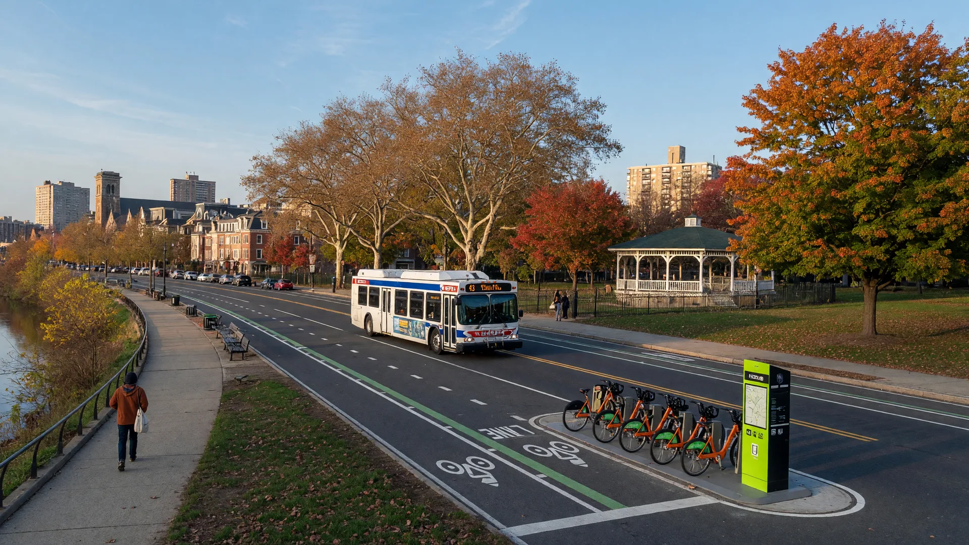 Schuylkill River Trail in Fitler Square with a walker, SEPTA bus, bike lanes, and Indego bike share station on a sunny autumn morning