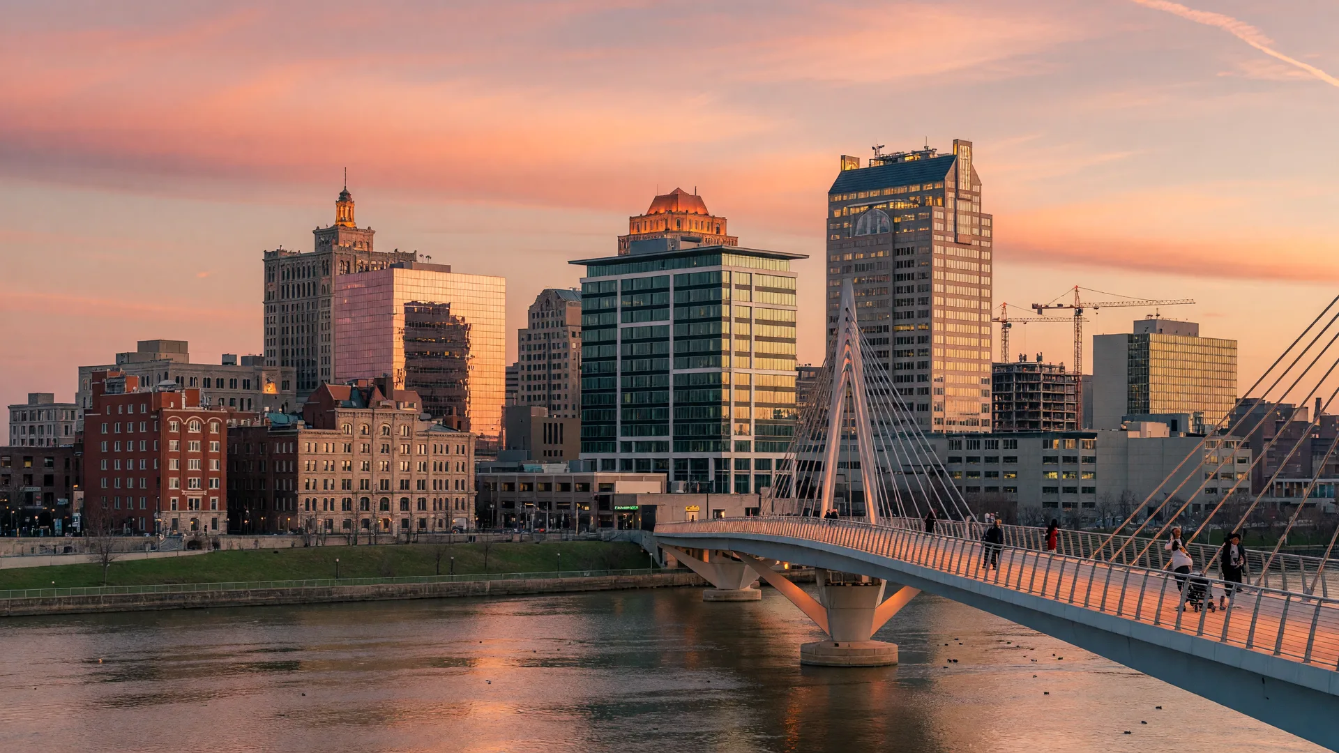 Dayton Ohio downtown skyline at golden hour with the Great Miami River and pedestrian bridge in the foreground