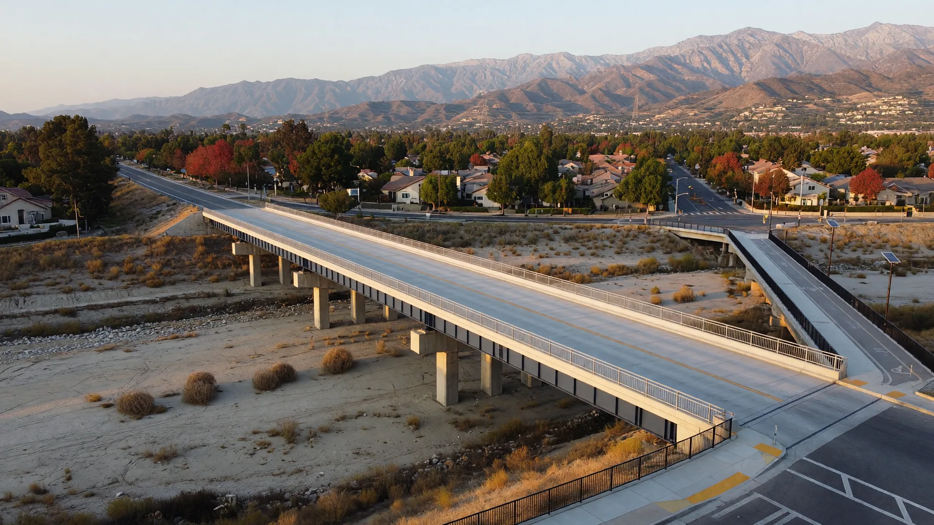 A new two-lane bridge with a separate pedestrian and cyclist path crossing a dry riverbed near Santa Clarita neighborhoods
