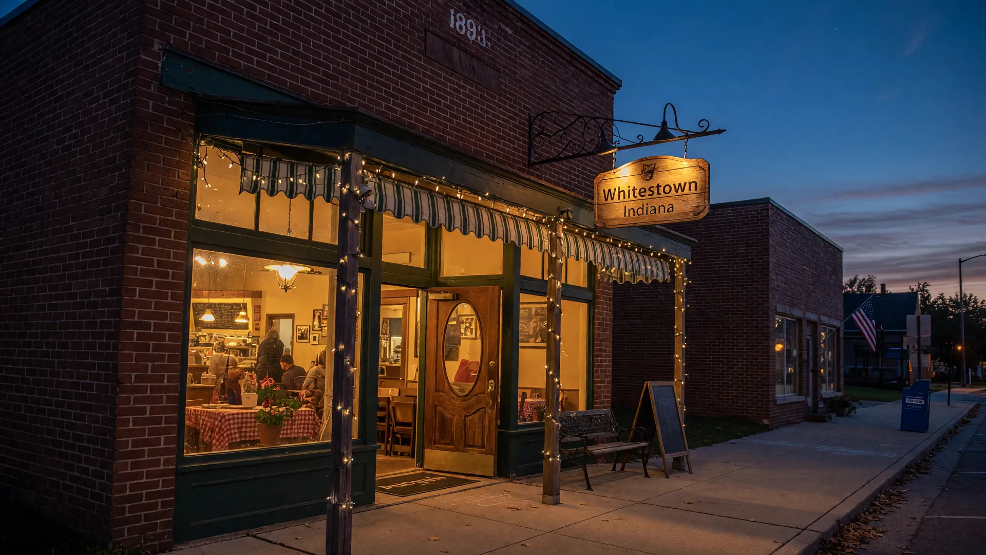 L.A. Cafe on Whitestown Indiana's small-town Main Street, a historic brick storefront glowing warmly at dusk with string lights and a welcoming family-owned restaurant atmosphere