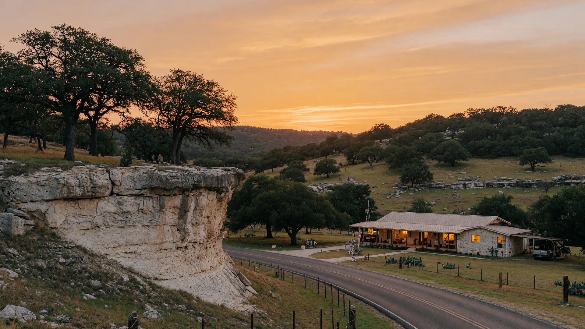 Limestone bluff and live oaks above a country road near Helotes at sunset, a Hill Country San Antonio real estate scene