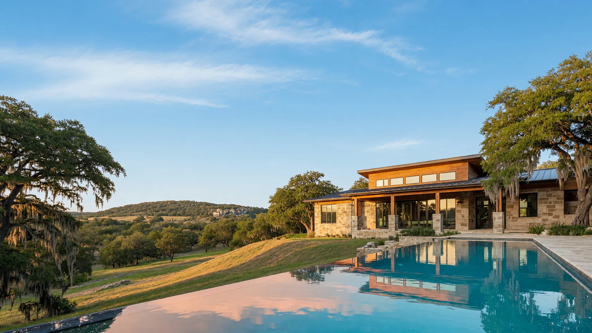 Modern Texas Hill Country home with a glowing pool and sweeping evening views