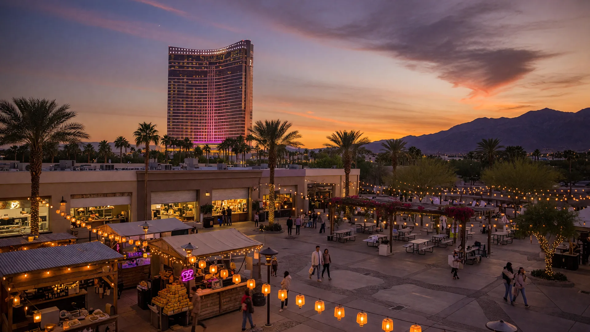 Dusk at a Southwest Las Vegas dining and entertainment district with a glowing resort tower on the horizon, string lights between palm trees, and market stalls in the foreground