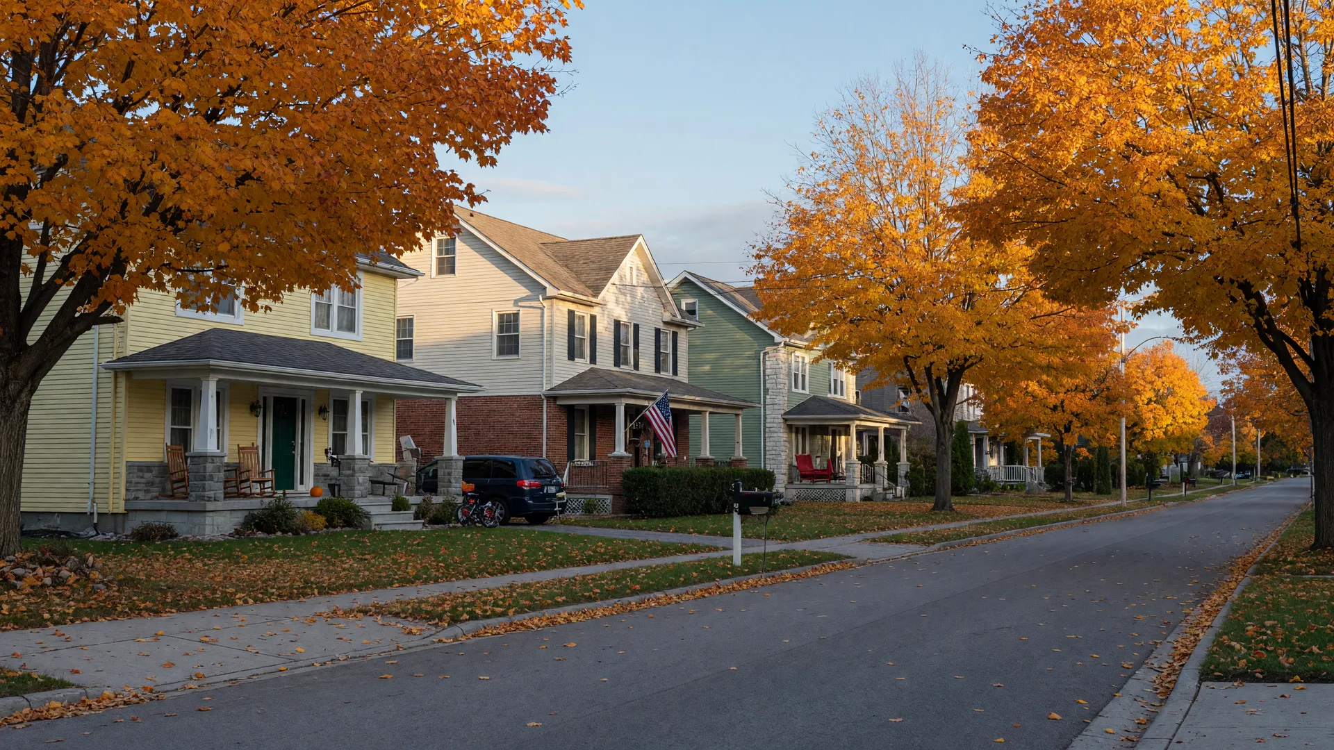 A quiet, tree-lined residential street in Port Perry on an October morning, with two-storey family homes, front porches and maples in full autumn colour