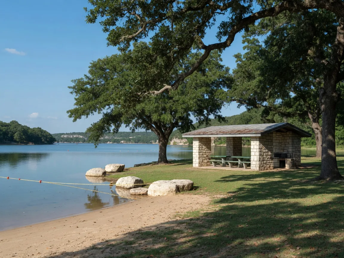 Lakeside Park on Lake Marble Falls with a sandy beach,and roped swim area,live oaks,limestone boulders,and a vintage stone picnic shelter