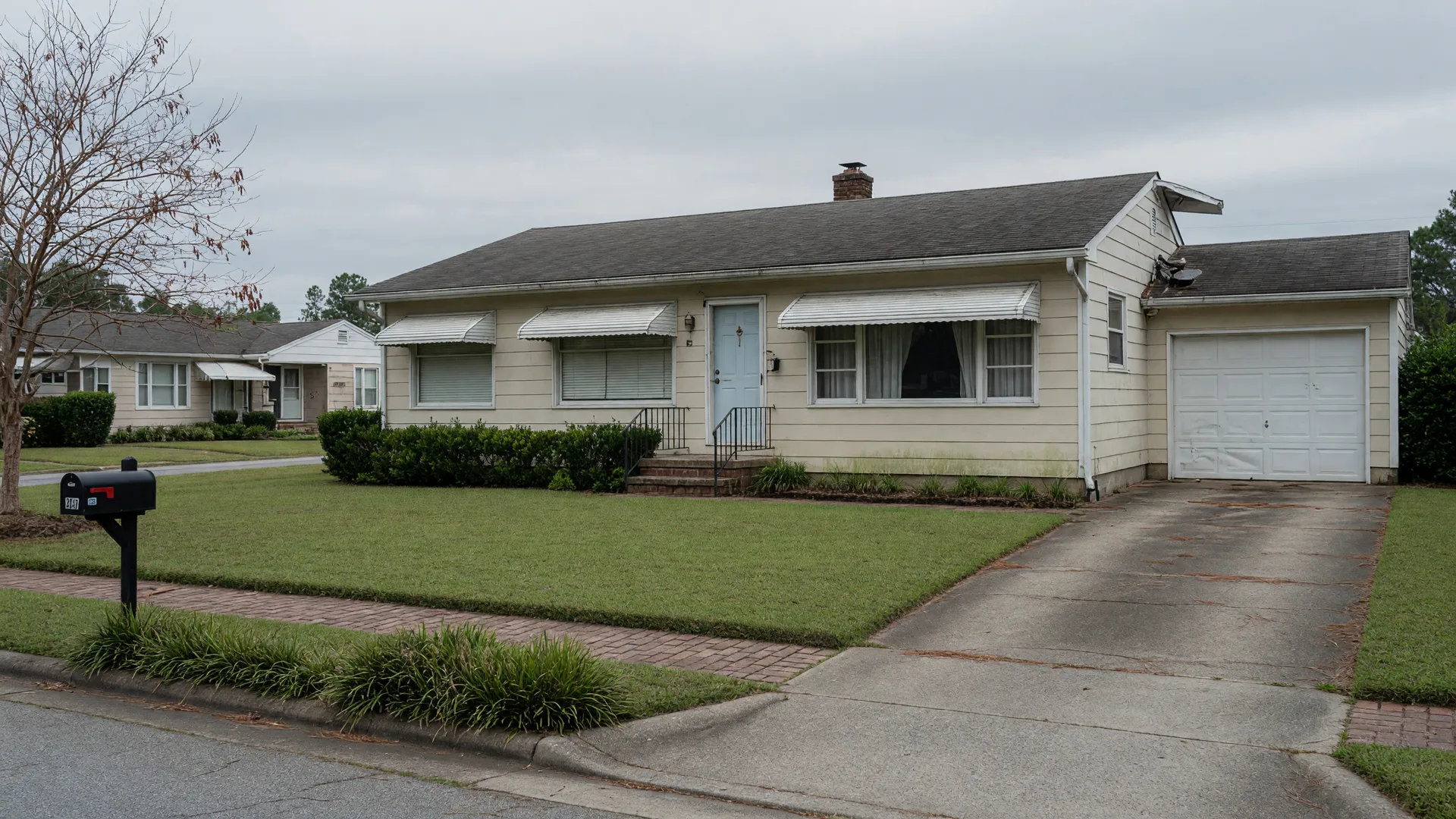 Quiet vacant single-family home exterior on an overcast afternoon with an empty driveway and unstirred lawn