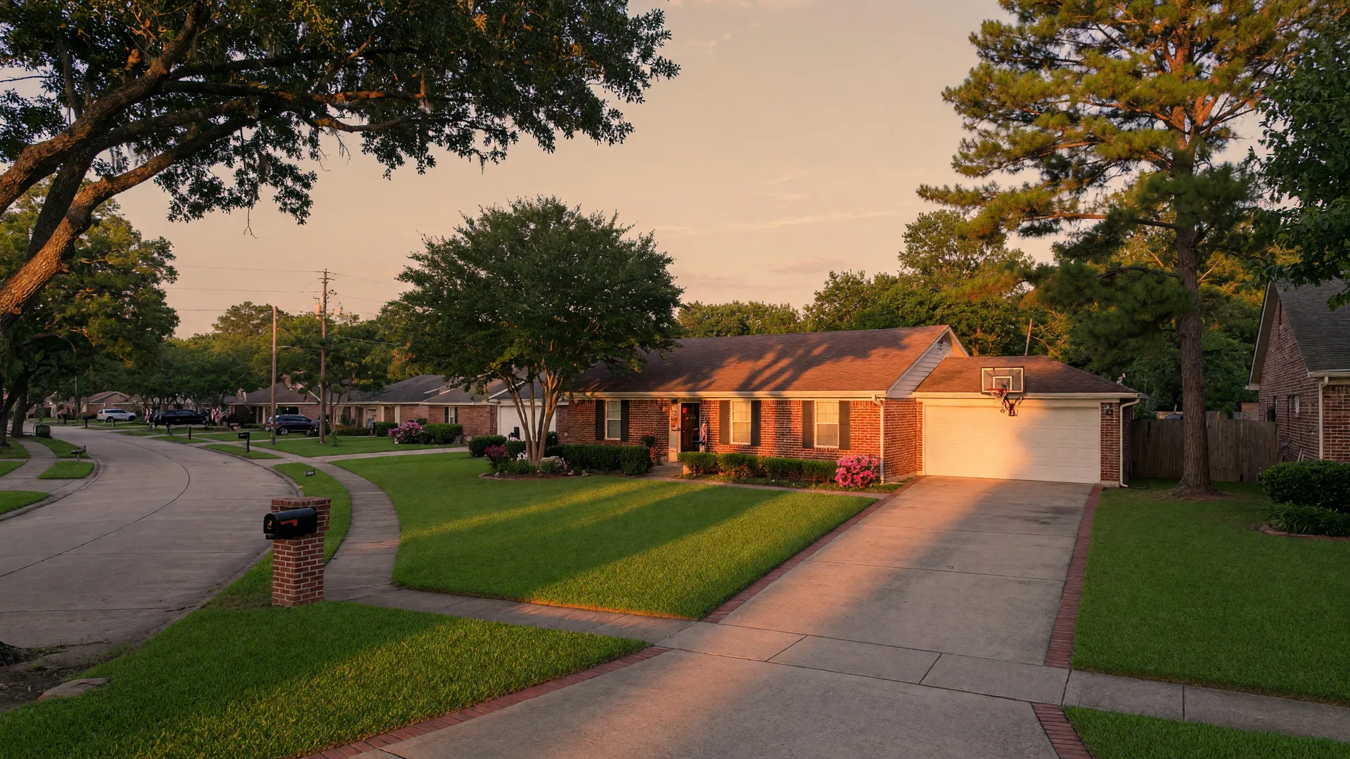 A well-maintained single-story brick home on a tree-lined suburban street in the Northeast Houston area at golden hour, with a manicured lawn and a driveway leading to an attached garage