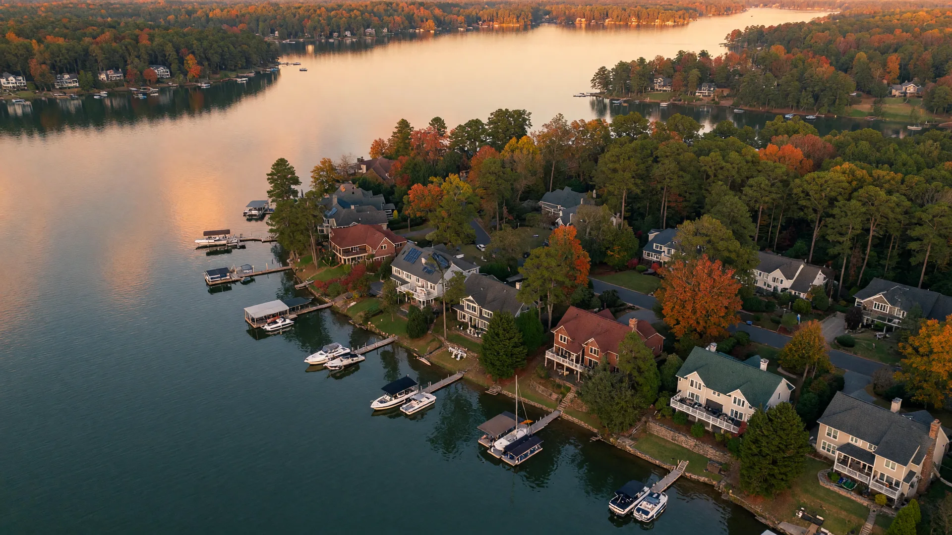 Aerial view of a Lake Norman waterfront residential community with private docks at golden hour