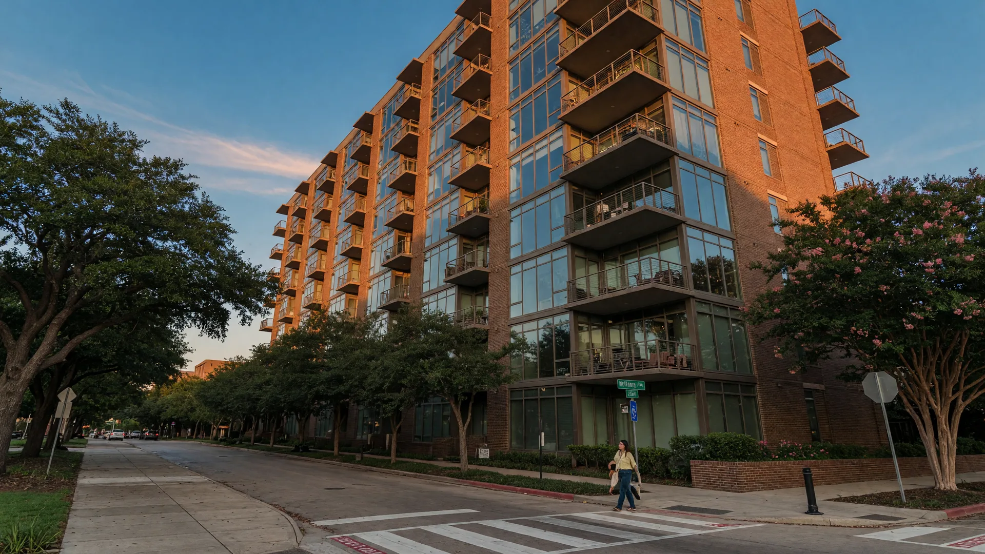 Mid-rise condominium building in Uptown Dallas with balconies and floor-to-ceiling glass in late afternoon light