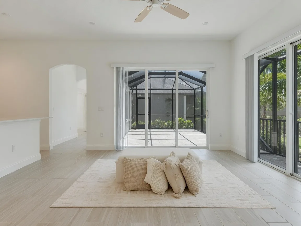 A freshly staged, bright Florida living room with natural light and a screened lanai beyond