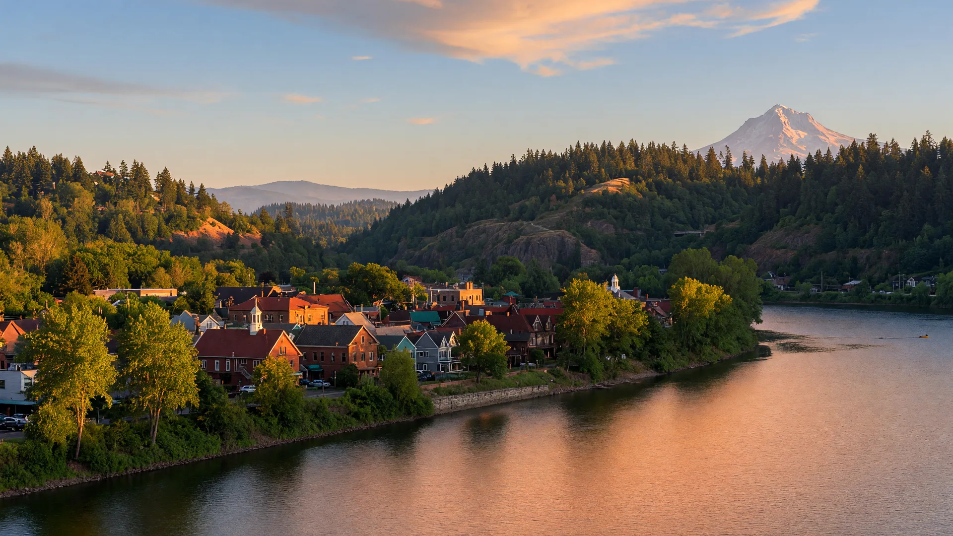 The Willamette River at West Linn at golden hour with the historic Willamette district along the riverbank and wooded hills behind
