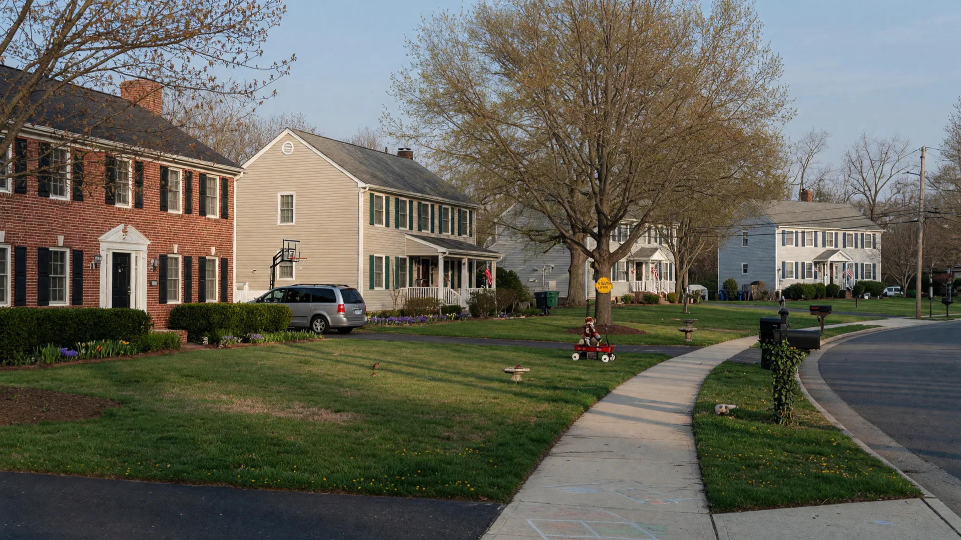 A well-kept Northern Virginia suburban street in early spring with brick and siding homes, lawns, and mature trees