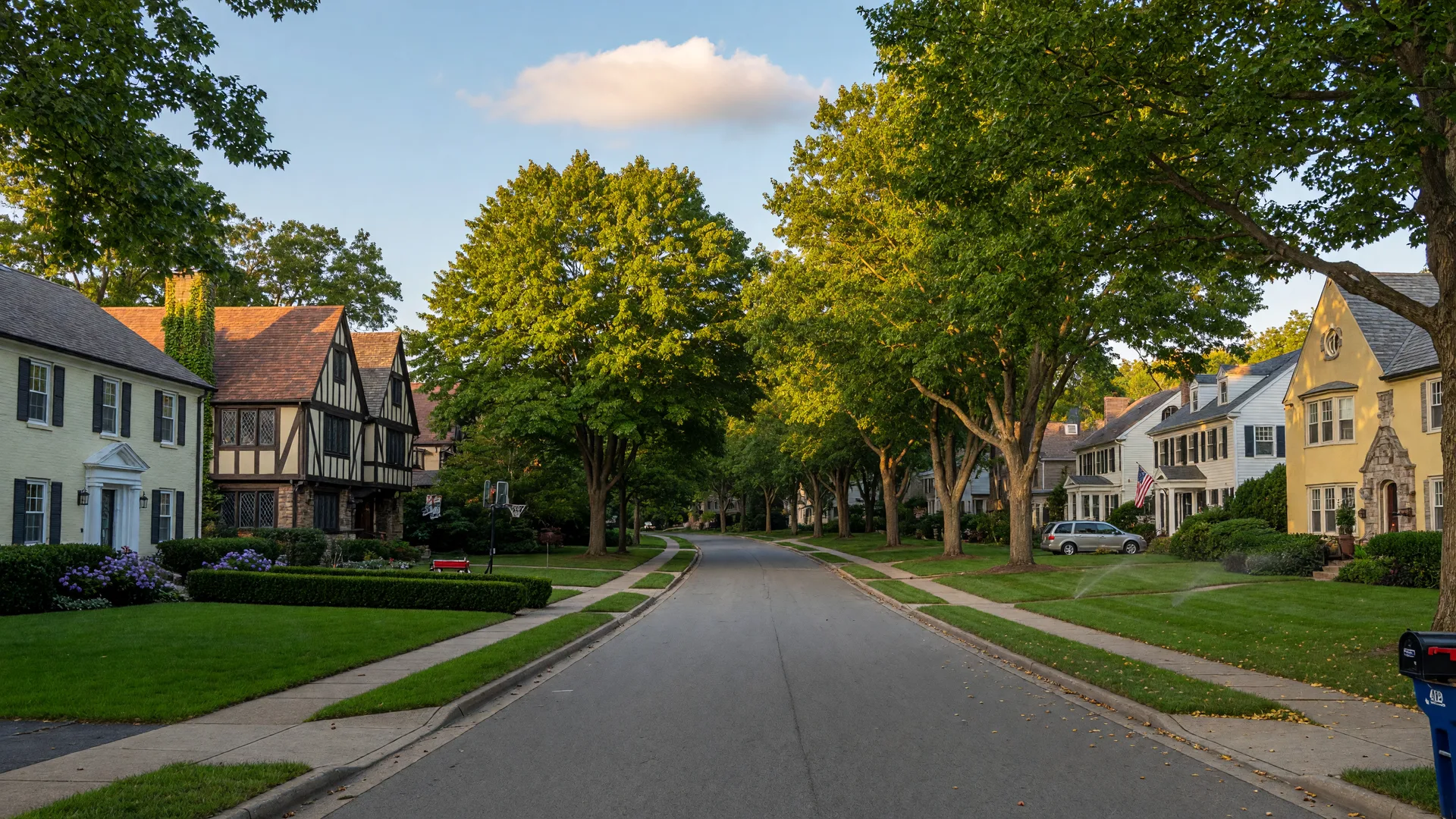 Tree-lined suburban street in Westlake, Ohio with well-maintained Colonial and Tudor-style homes on a sunny summer afternoon