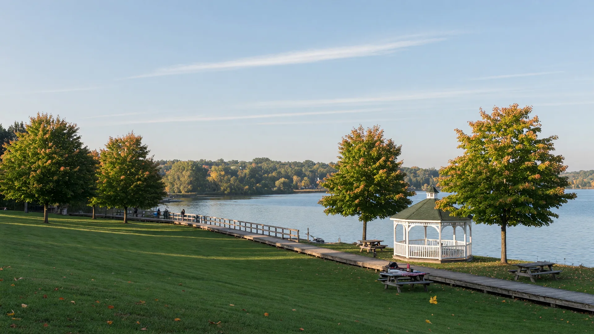 Palmer Park on the Lake Scugog waterfront in Port Perry, green lawns and maple trees beside a wooden boardwalk and calm water on a September morning